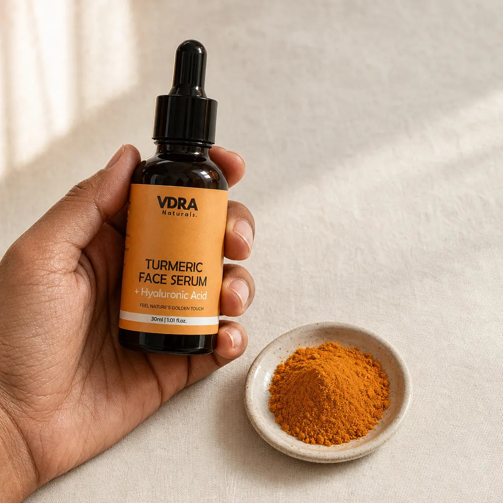 Hand holding VDRA Turmeric Face Serum bottle next to turmeric powder