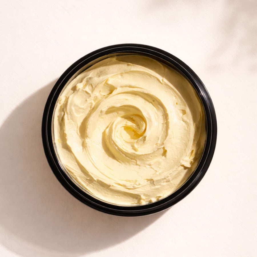 Black container of golden turmeric clay mask texture being swirled
