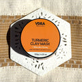 Jar of VDRA Naturals Turmeric Clay Mask with Manuka Honey on a textured background surface