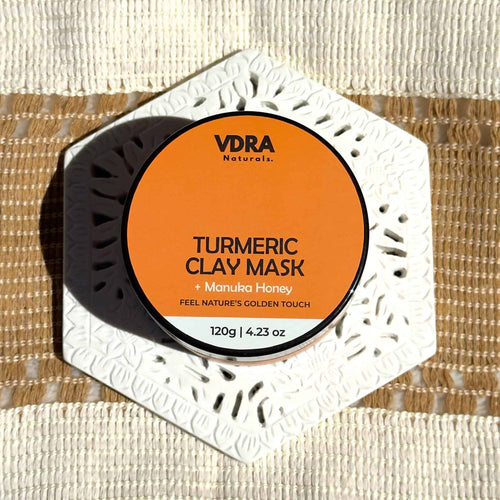 Jar of VDRA Naturals Turmeric Clay Mask with Manuka Honey on a textured background surface
