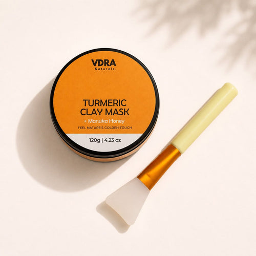 VDRA Naturals turmeric clay mask with manuka honey, 120g amber jar. Clay mask applicator tool next to it. 