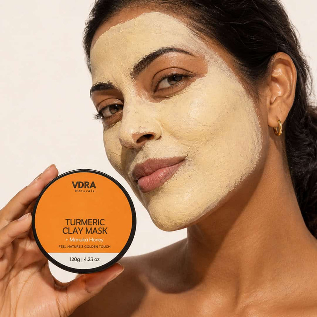 Woman with melanin-rich skin applying VDRA turmeric clay mask for dark spots