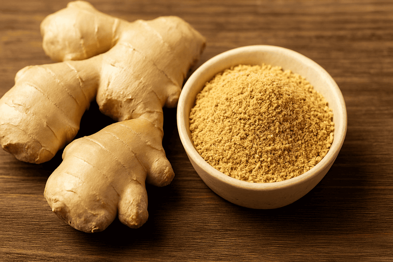 Ginger root and ground ginger powder on a wooden surface