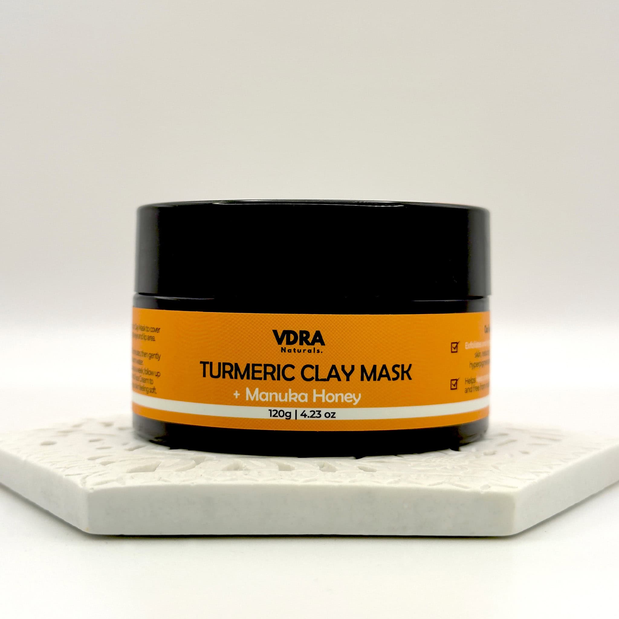 Jar of VDRA Naturals Turmeric Clay Mask with Manuka Honey on a white surface and a white background.