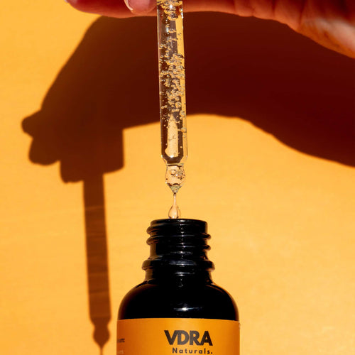 VDRA Naturals dropper bottle with liquid being dripped against an orange background