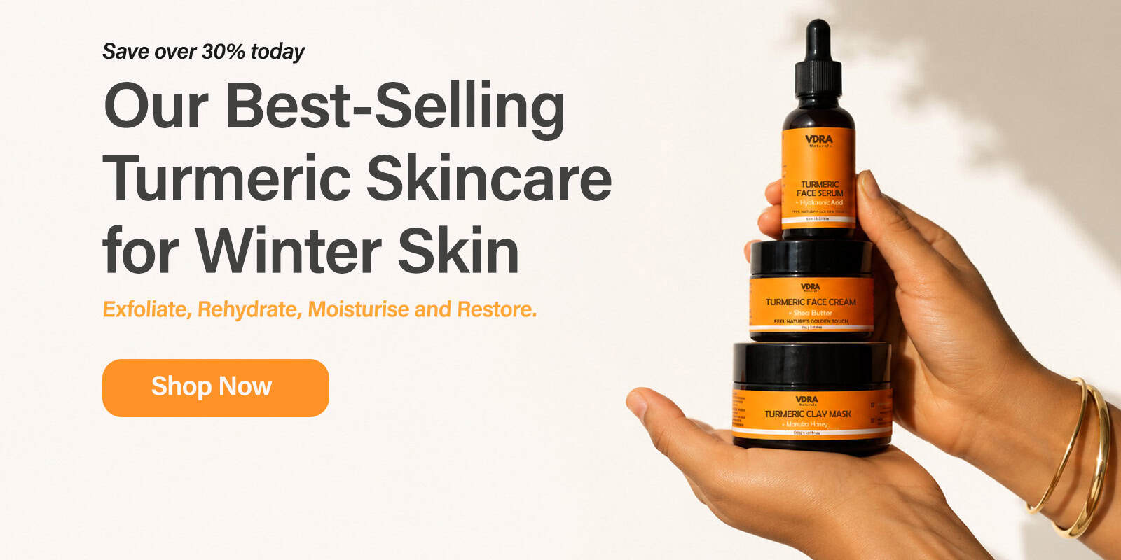 VDRA turmeric skincare products held by a hand with promotional text on a white background